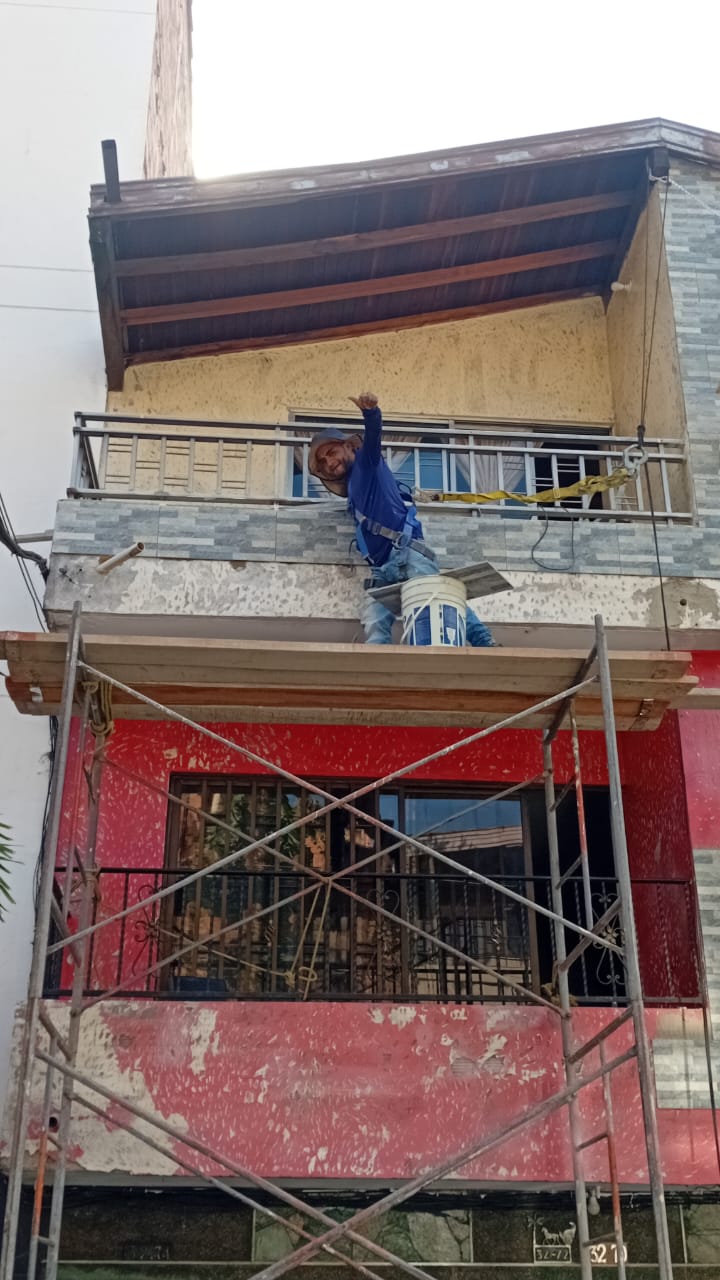 Obrero con arnés de seguridad terminando fachada