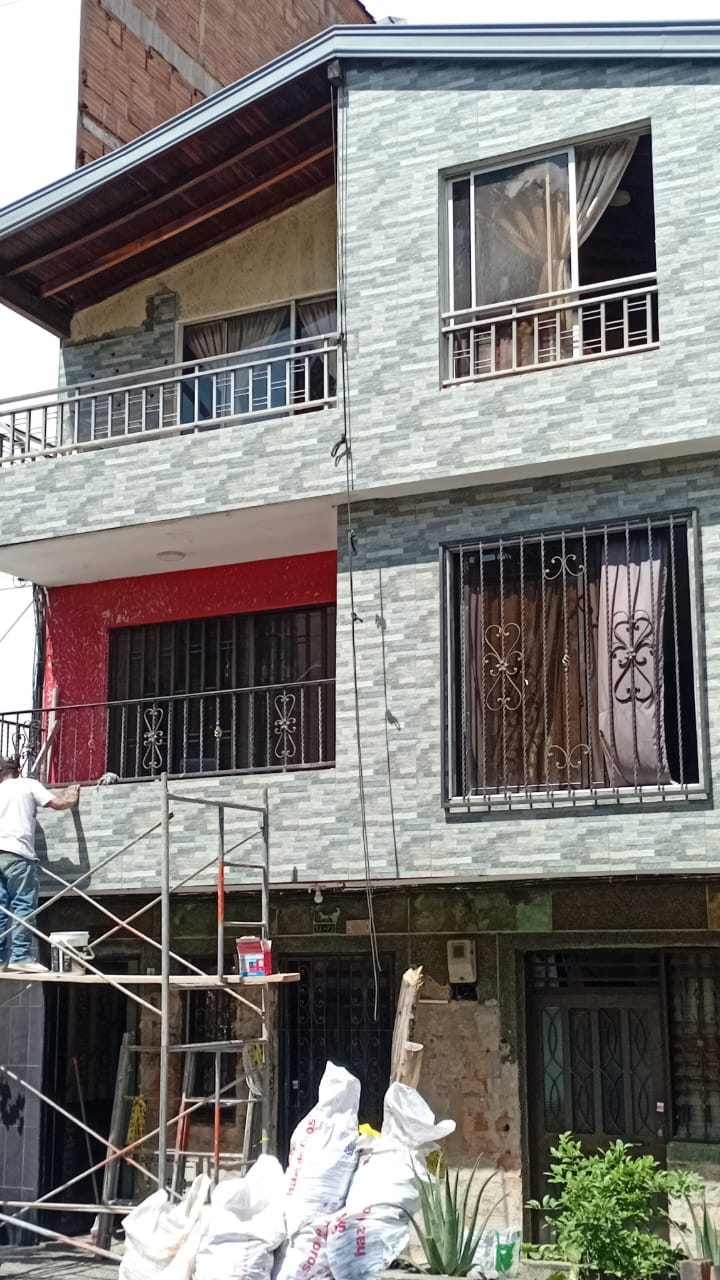Fachada con enchape en piedra y obrero en andamio
